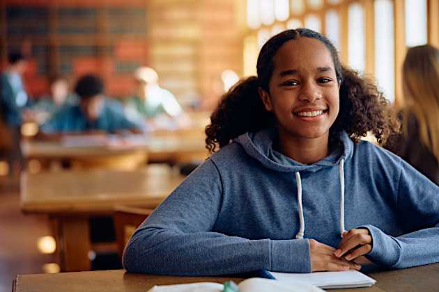 A young black woman is in a library studying. 