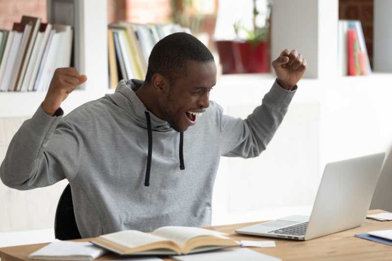 A young man is looking at this laptop and is very excited about what he sees. 