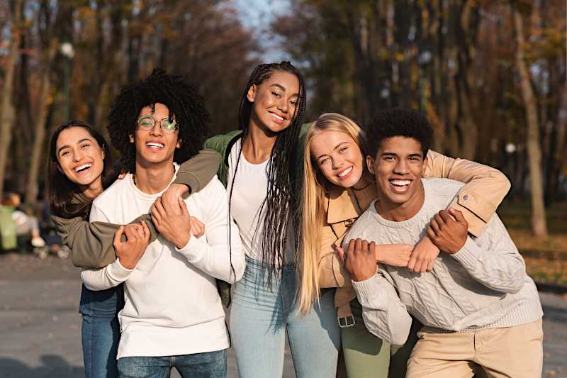 A group of young people are hugging and smiling. 